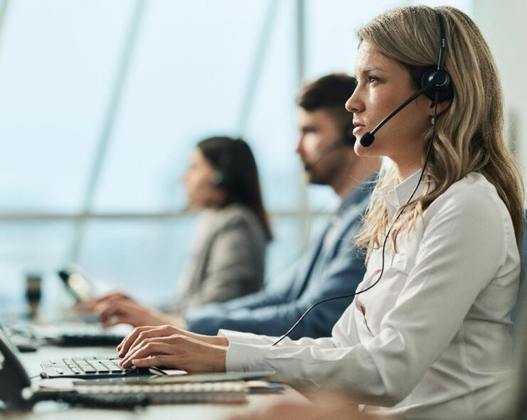 Young businesswoman and her colleagues working on desktop PC in a call center.