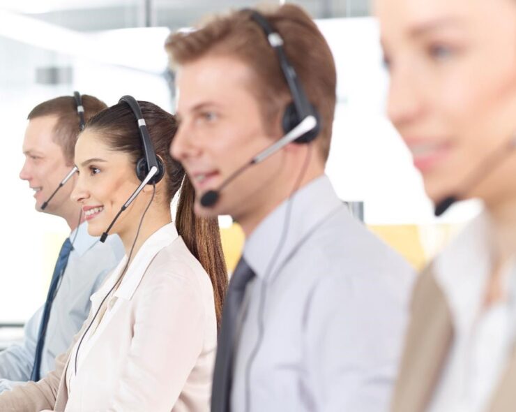 Four call center operators, wearing headsets, looking happy