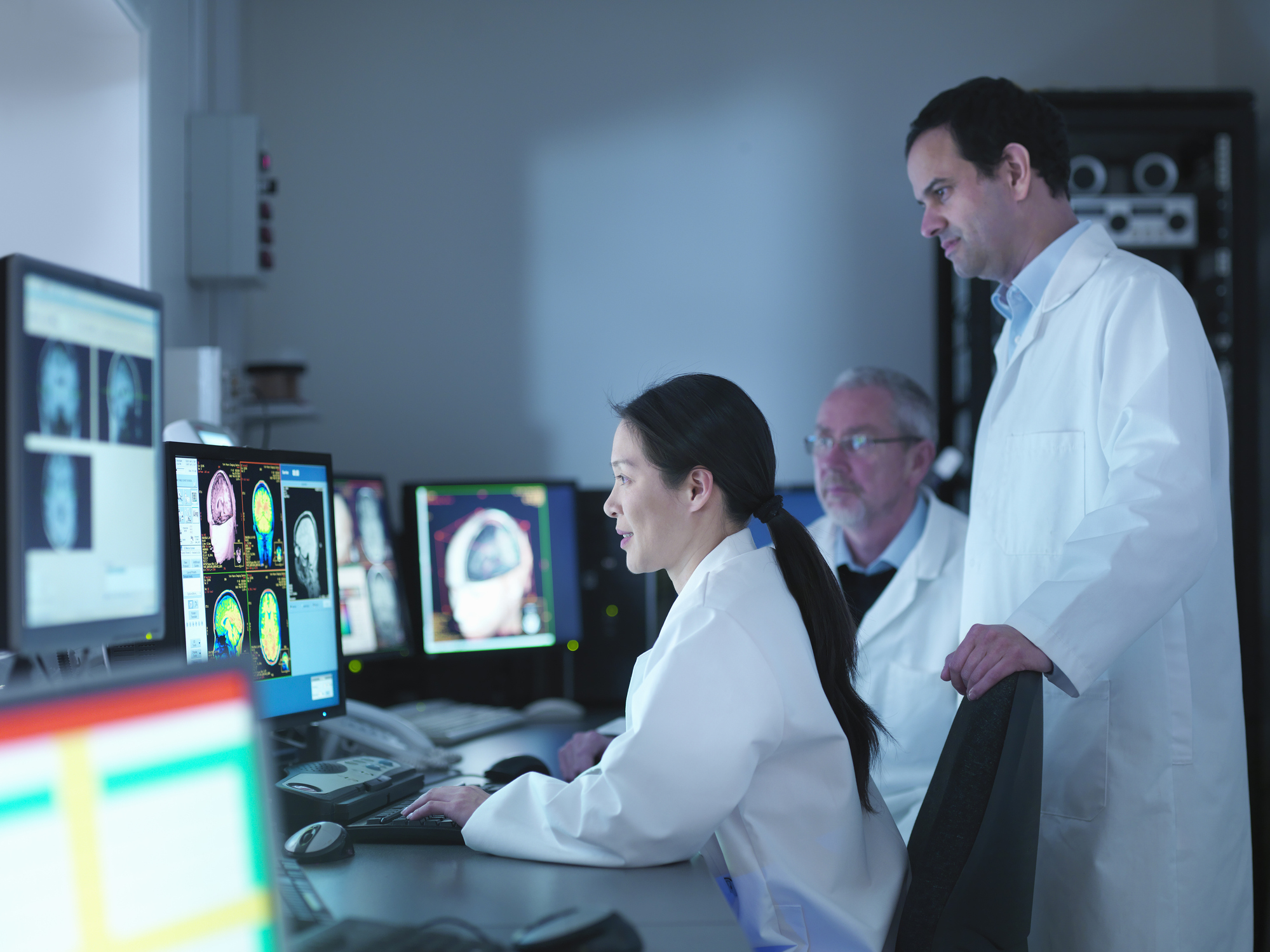 Doctors and scientists looking at screens of Magnetic Resonance Imaging (MRI) 3 Tesla twin speed scanner