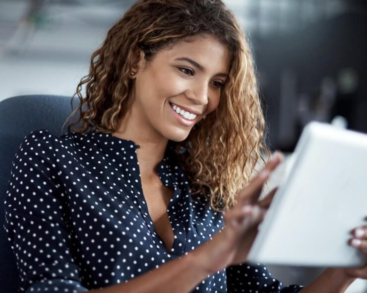 A young woman working on a digital tablet in a modern office