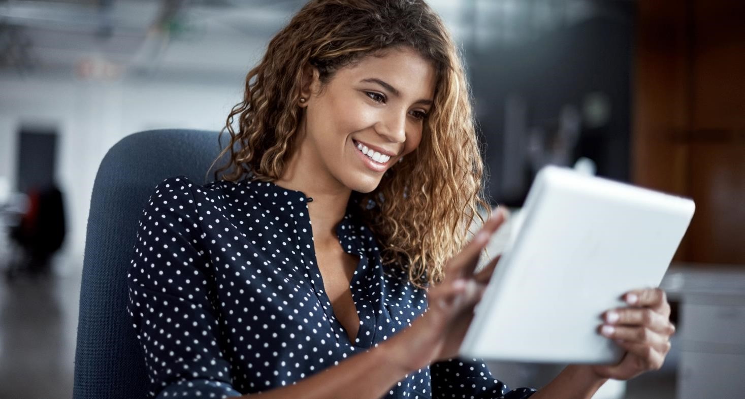 A young woman working on a digital tablet in a modern office