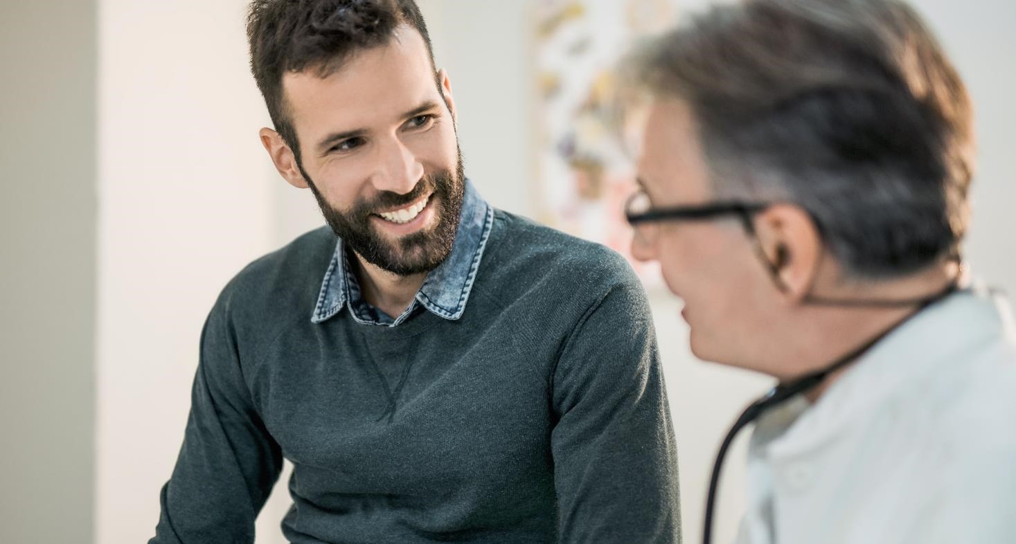 Happy mid adult male patient talking with his doctor.