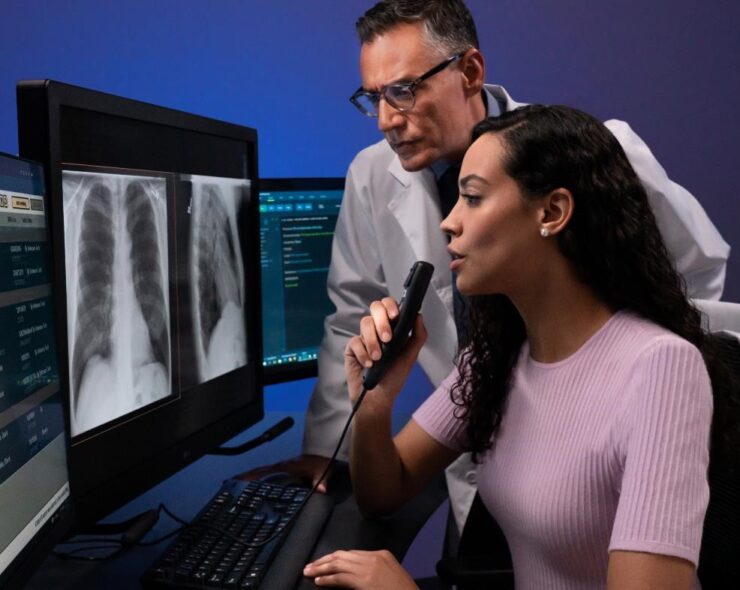 A male and female MRI technologist sitting at the console in the operating room and operating the MRI scanner