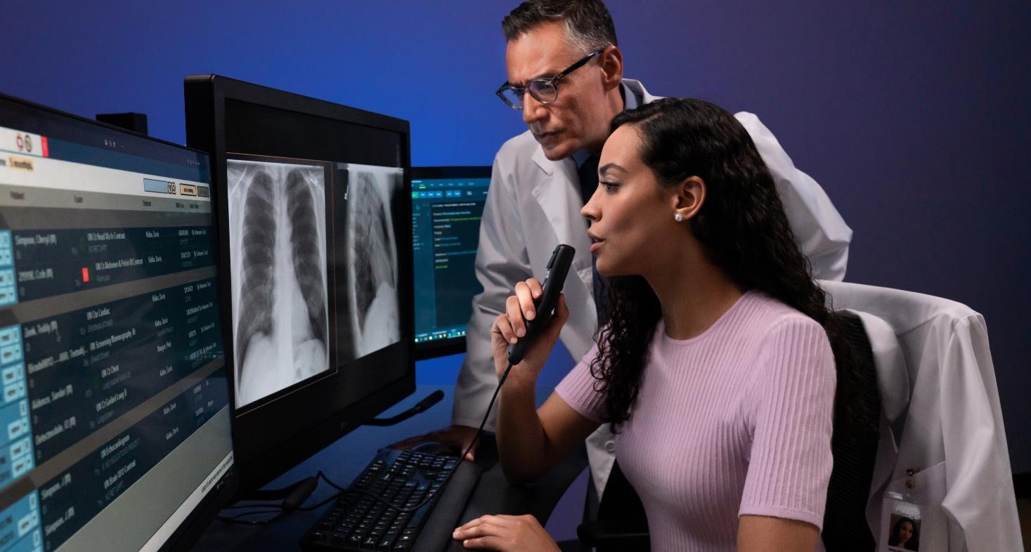 A male and female MRI technologist sitting at the console in the operating room and operating the MRI scanner