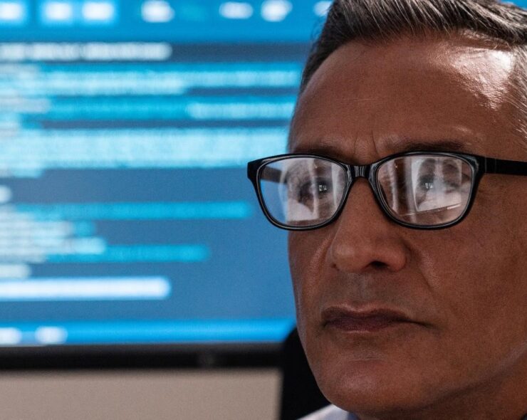 A close up of a male radiologist looking at an x-ray with the reflection showing in his spectacles.